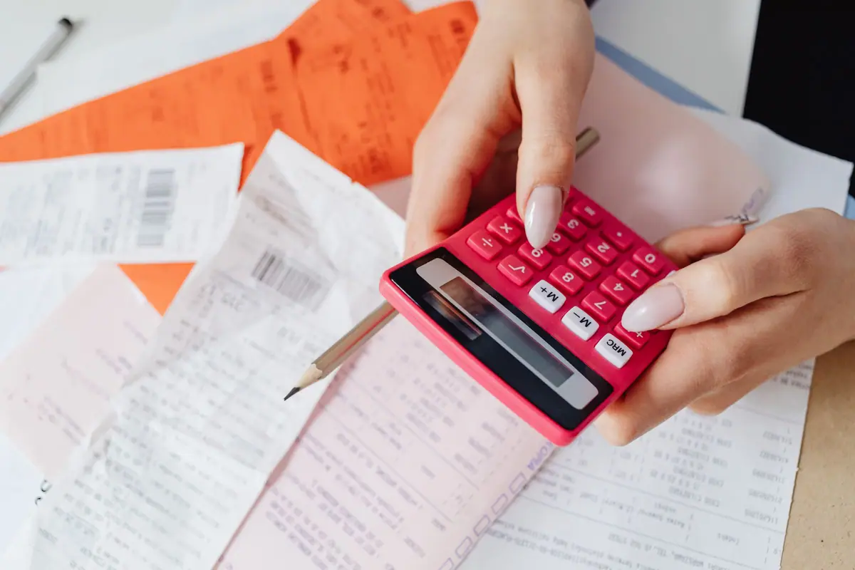 Mãos com uma calculadora sobre uma pilha de recibos
