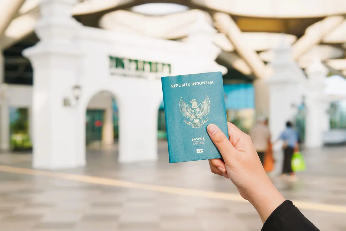 A hand holding a passport in an airport terminal