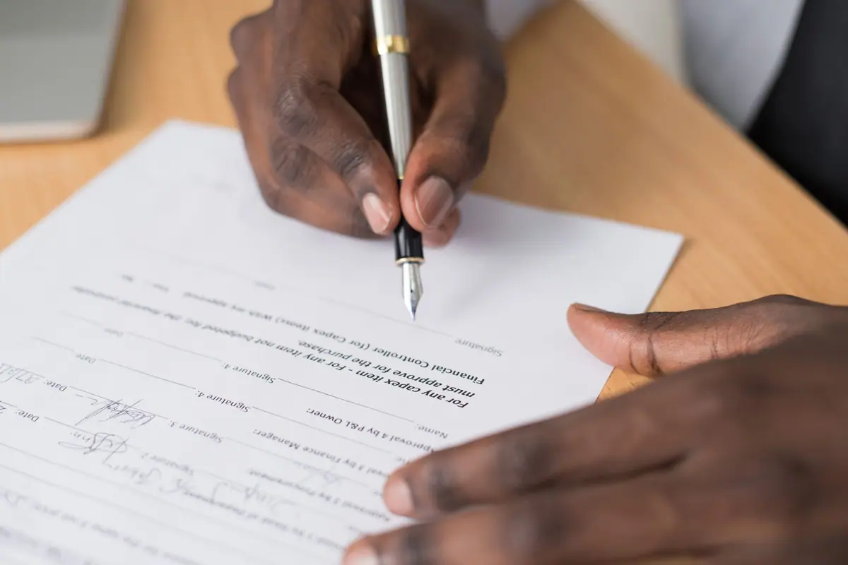 Hands signing a formal document