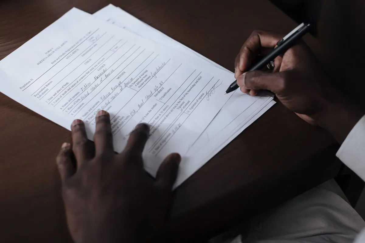 Hands signing official papers at a table