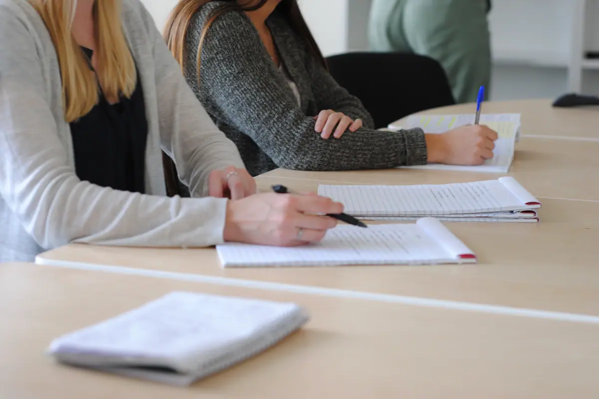 Alunos adultos fazem anotações em sala