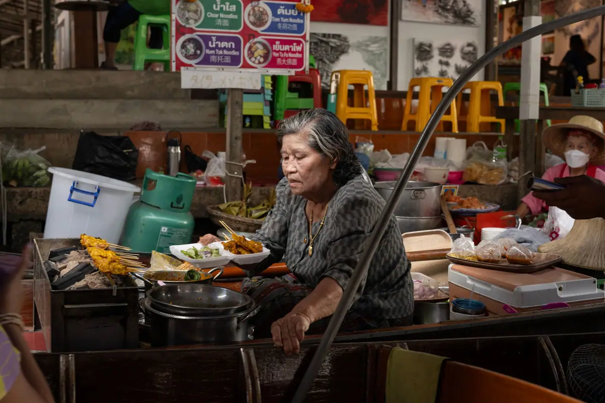 Eine Frau kocht auf einem thailändischen Straßenmarkt