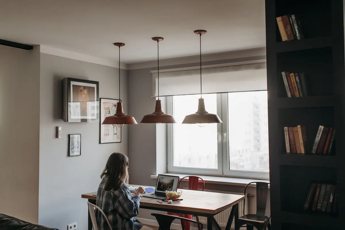 Uma mulher trabalha no notebook em um apartamento iluminado